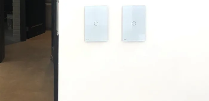 Interruptores ION Glass blancos instalados en pared blanca — espacio contemporáneo con puerta de vidrio