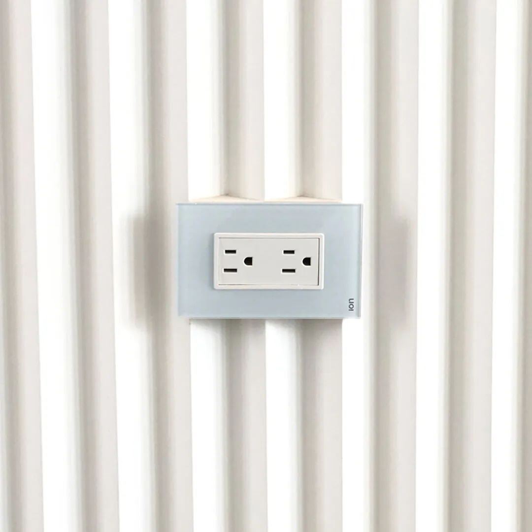 Tomacorriente ION Glass blanco en pared acanalada — panel de vidrio templado acabado premium