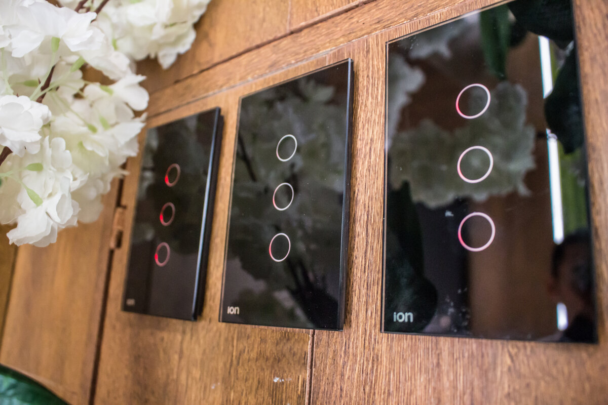 Interruptores Triple Glass ION negros instalados en pared de madera — 3 puntos touch en acabado negro