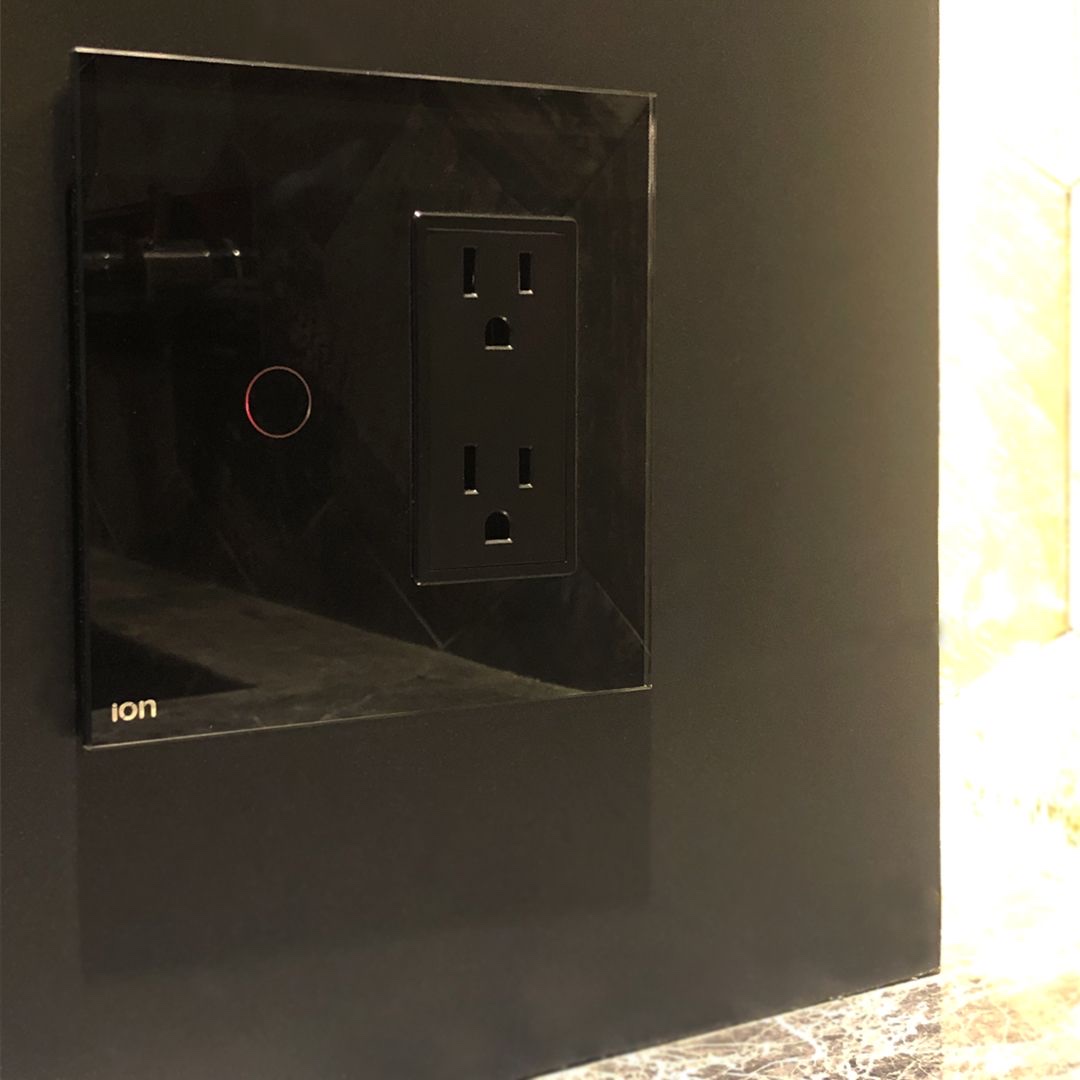 Módulo ION Style negro con interruptor y tomacorriente instalado en cocina de granito oscuro